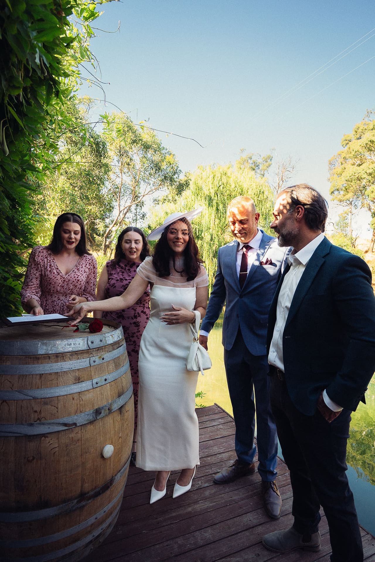 Kim laughing at the signing barrel on the deck with two women, Ben and a man in a dark suit