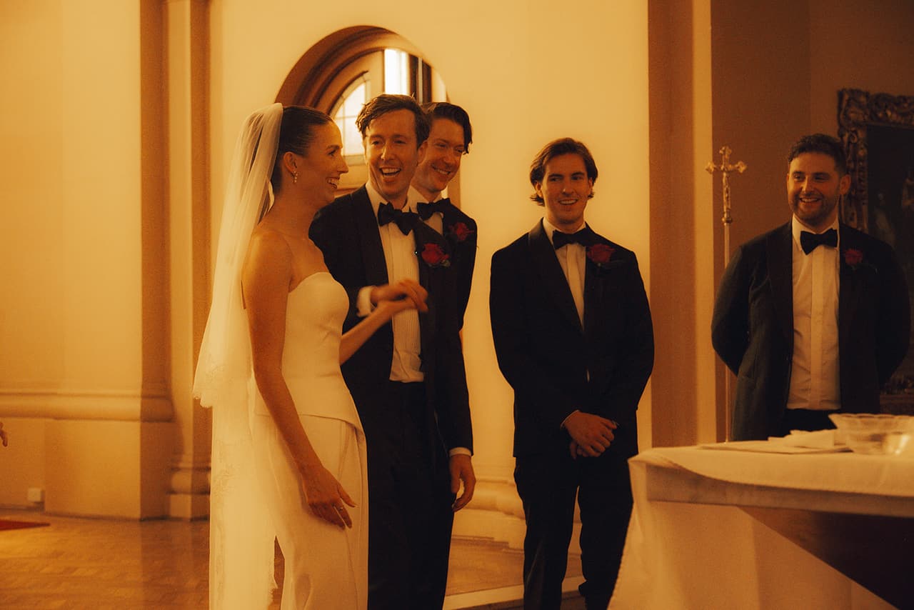 Kira and Nick laughing with the groomsmen beside the altar after the ceremony