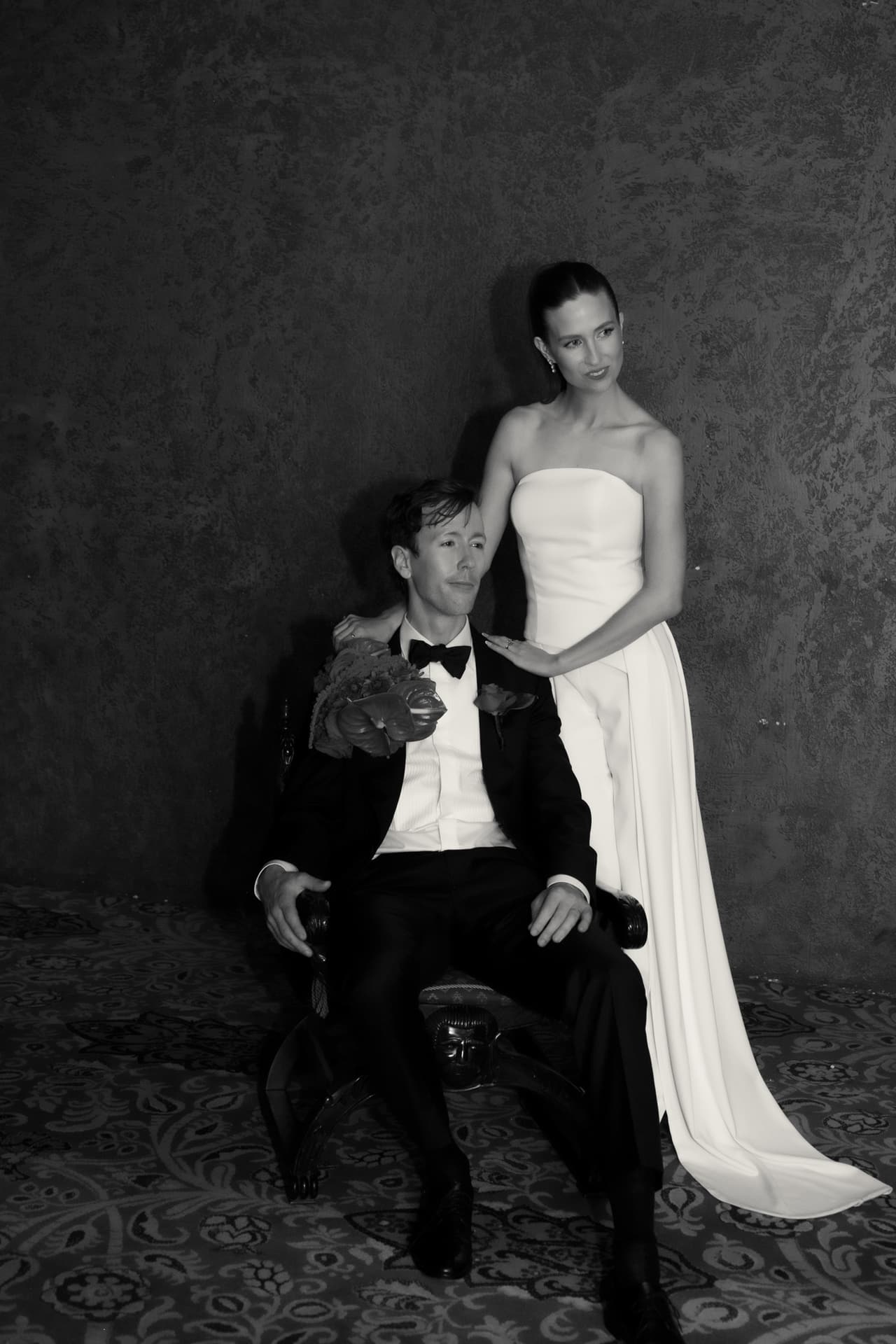 Black and white portrait of Nick seated in an armchair with Kira standing beside him in the Regent Theatre