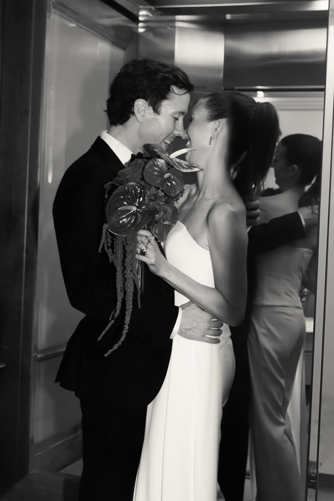 Black and white photo of Kira and Nick kissing in a hotel lift