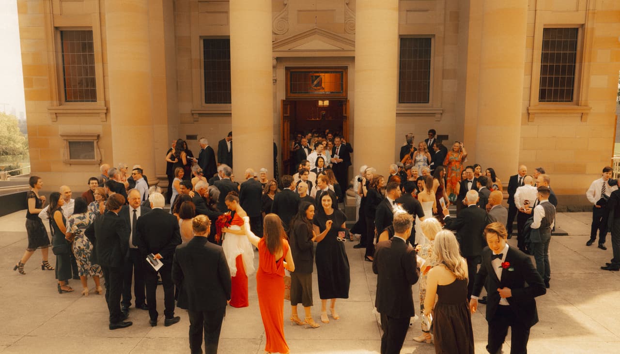 Guests gathering outside the sandstone chapel after the ceremony, seen from above