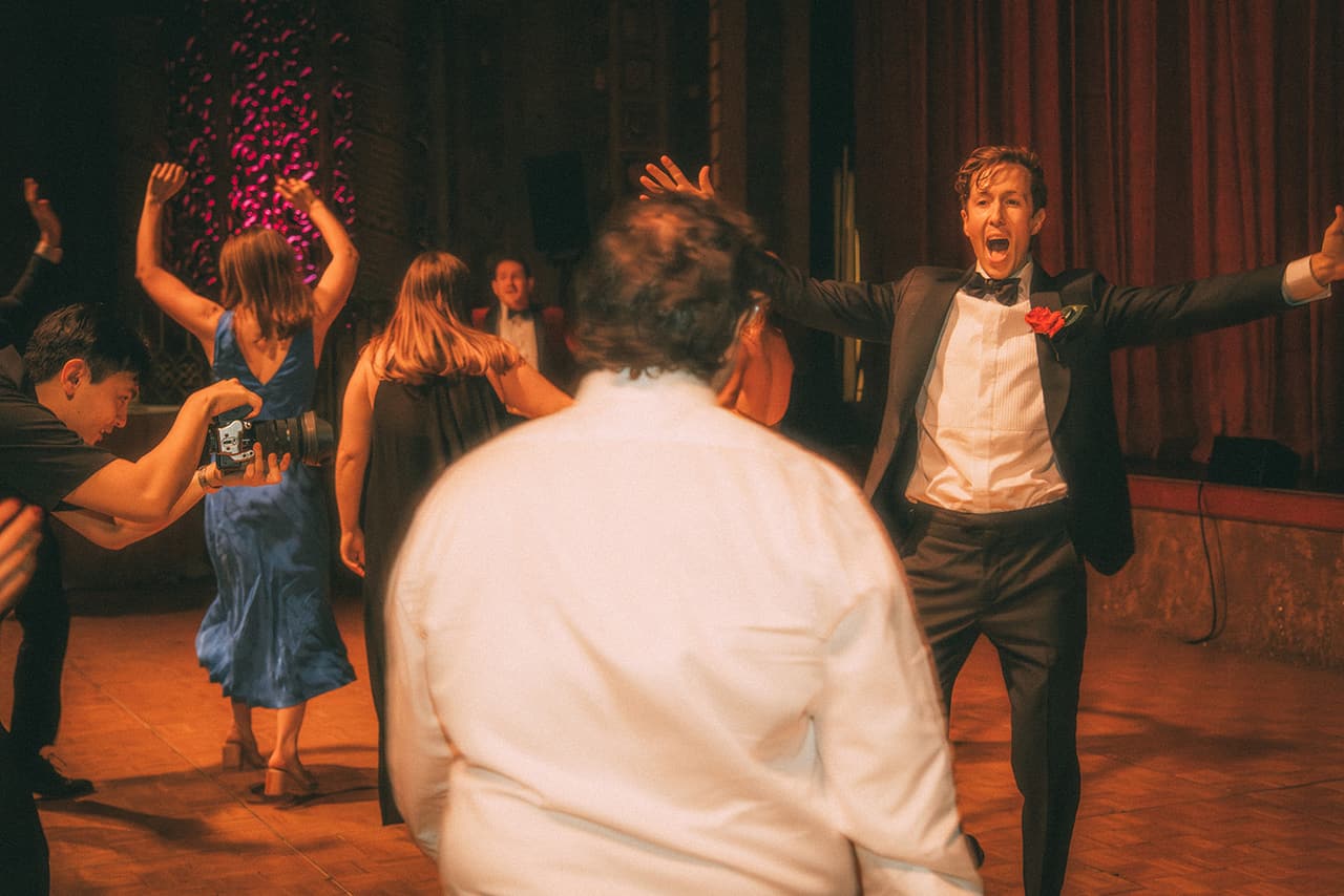 Nick dancing with his arms flung wide among guests on the dance floor