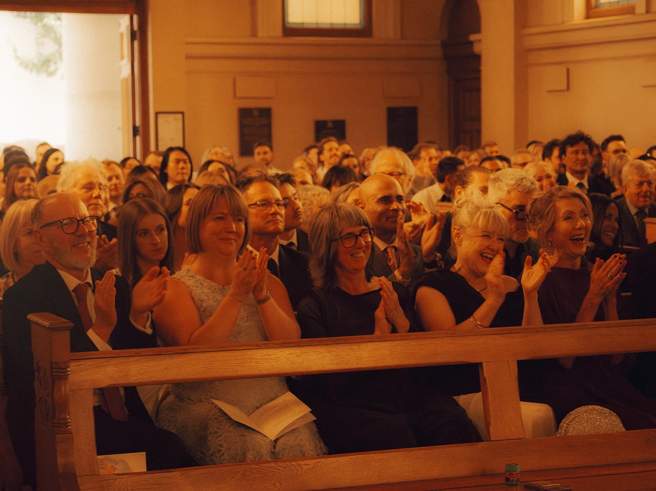 Guests in the pews clapping and laughing at the end of the ceremony