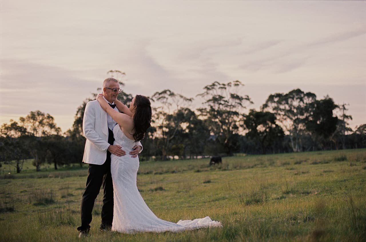 Kristie and Gareth holding each other in the paddock at sunset, on 35mm film