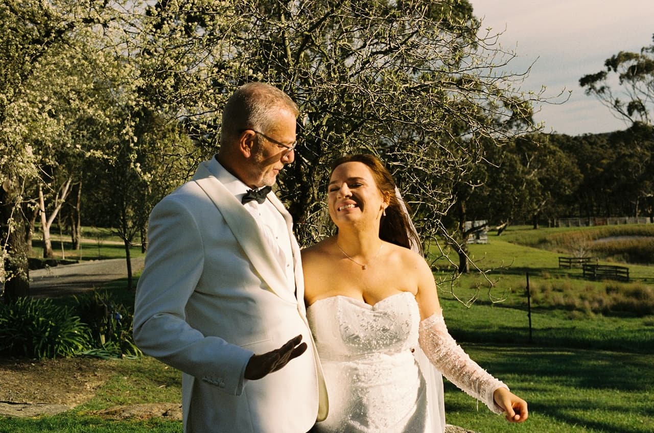 Gareth and Kristie laughing together in the garden after the ceremony, on 35mm film