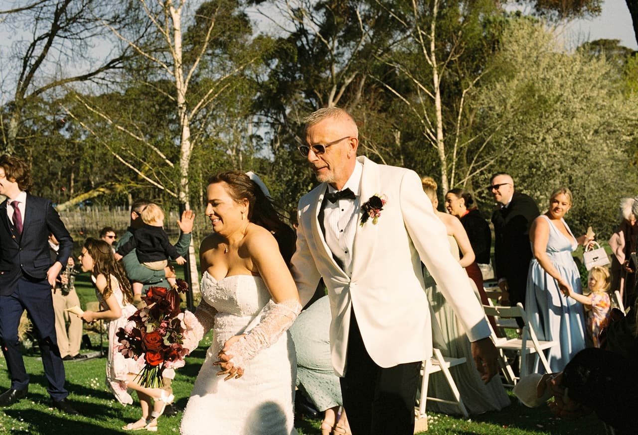 Kristie and Gareth walking back up the aisle past their cheering guests, on 35mm film