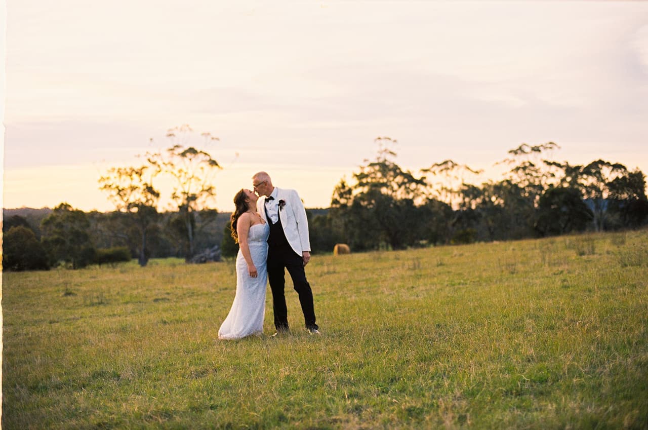 Kristie and Gareth in the open paddock under a soft evening sky, on 35mm film