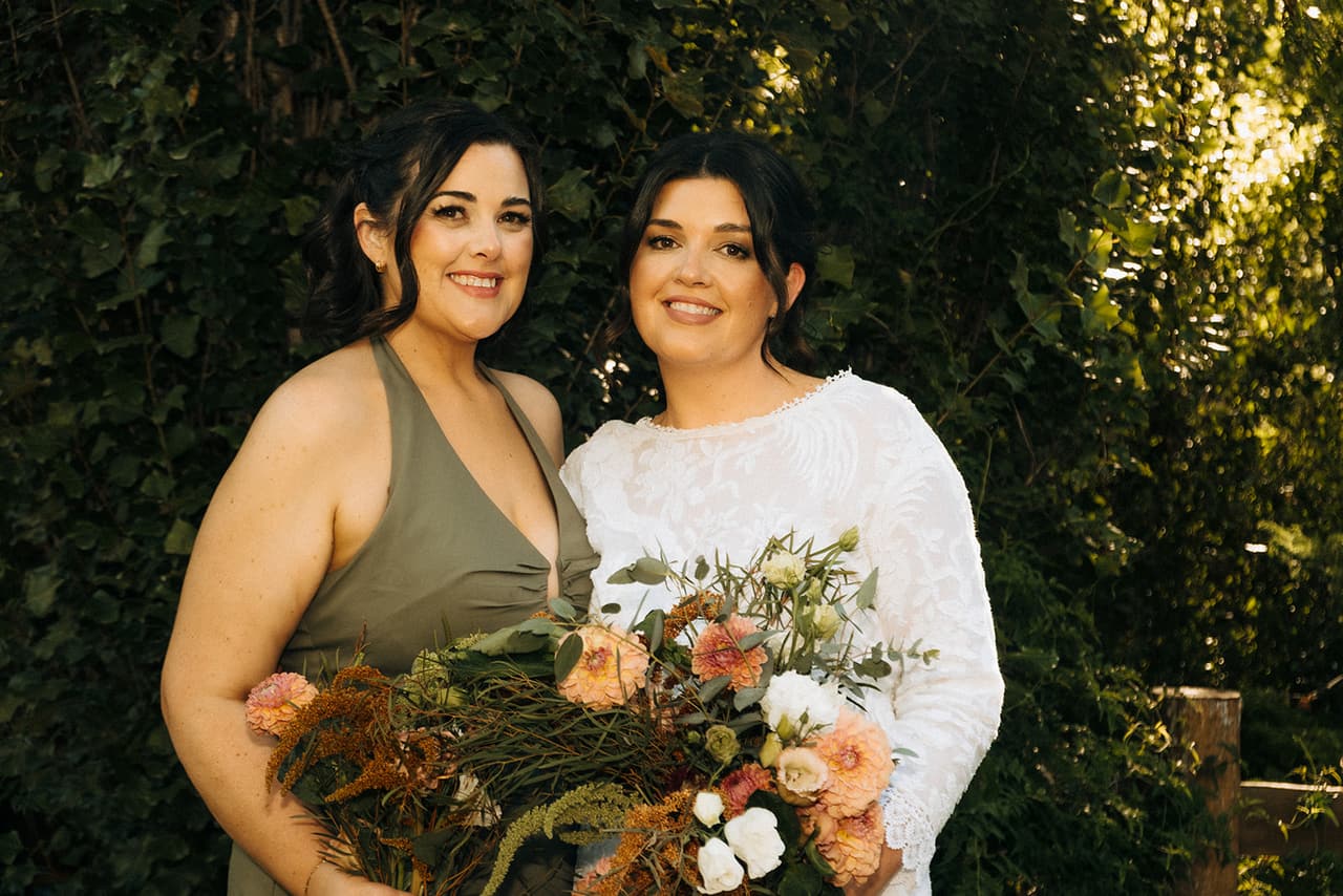 Lana with a bridesmaid, both holding bouquets of dried flowers in rust and cream