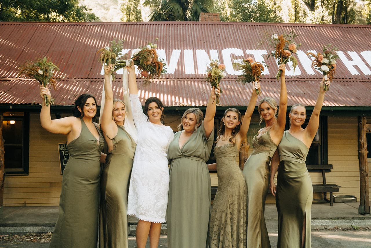 Lana and her bridesmaids raising their bouquets in front of the hotel