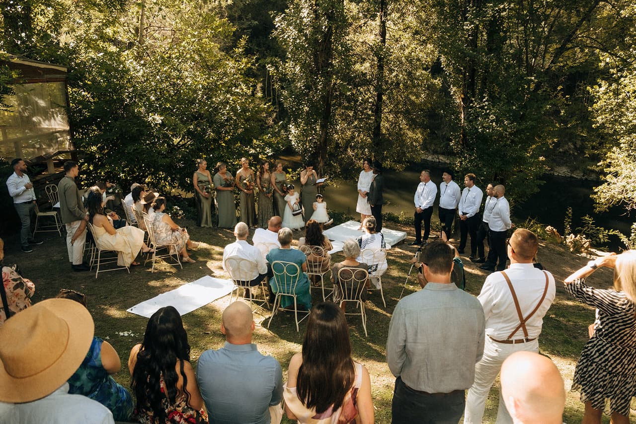Guests gathered around the ceremony under the tall trees