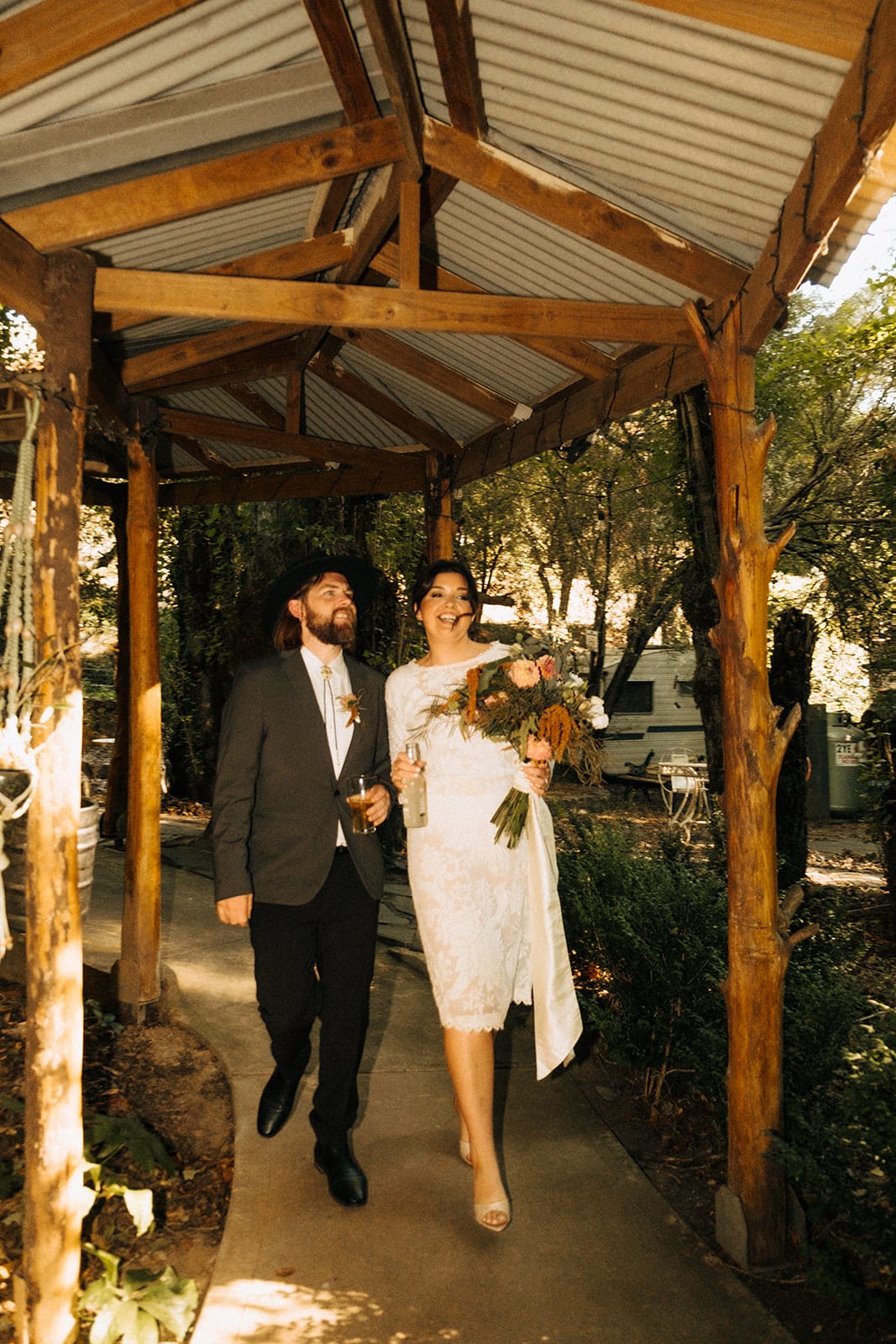 Lana and Todd walking arm in arm through a covered timber walkway to the reception