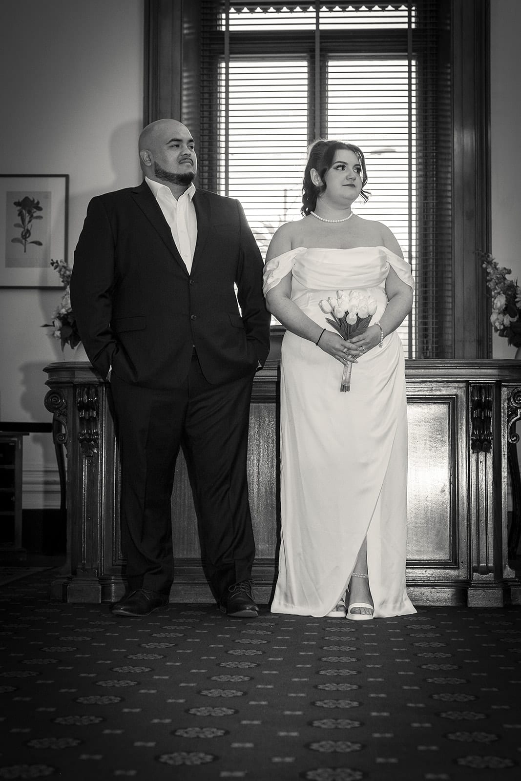 Black and white photo of Martina and Diego standing side by side at the registry desk before the ceremony