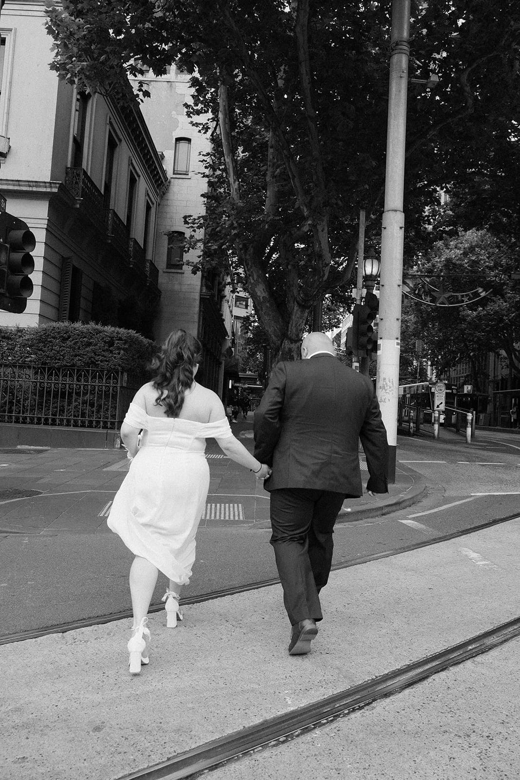 Black and white photo of Martina and Diego hurrying hand in hand across a city street