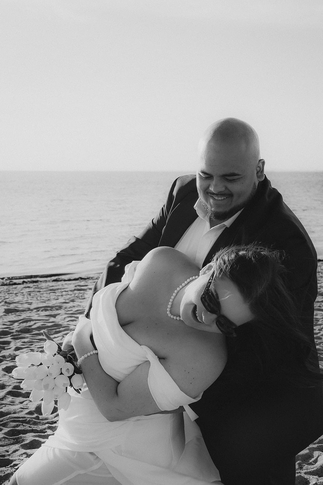 Black and white photo of Diego dipping Martina on the beach as they both laugh