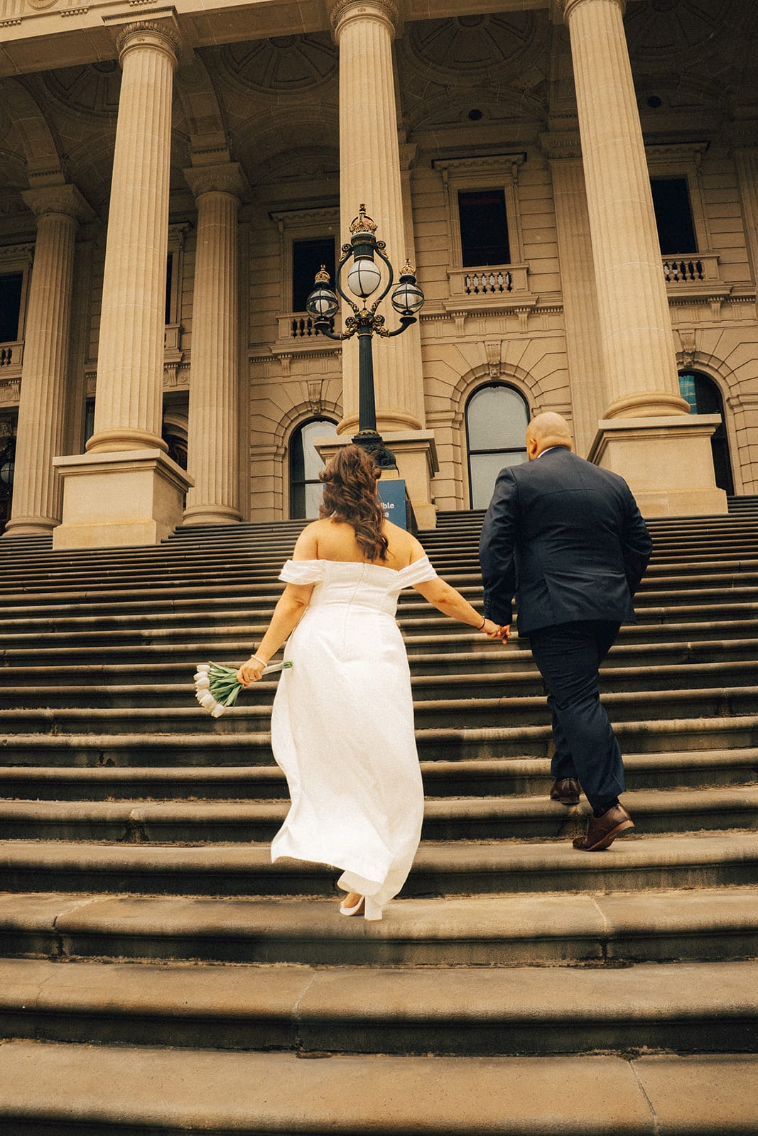 Martina and Diego climbing the wide steps of Parliament House hand in hand