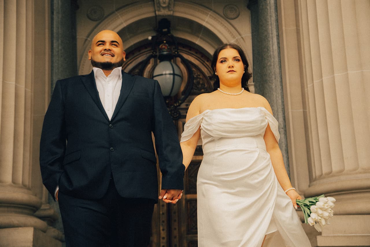 Martina and Diego walking hand in hand out from the doors of Parliament House
