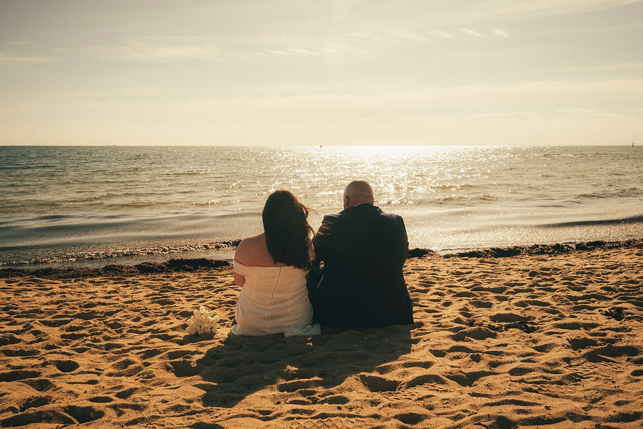 Martina and Diego sitting on the sand watching the water