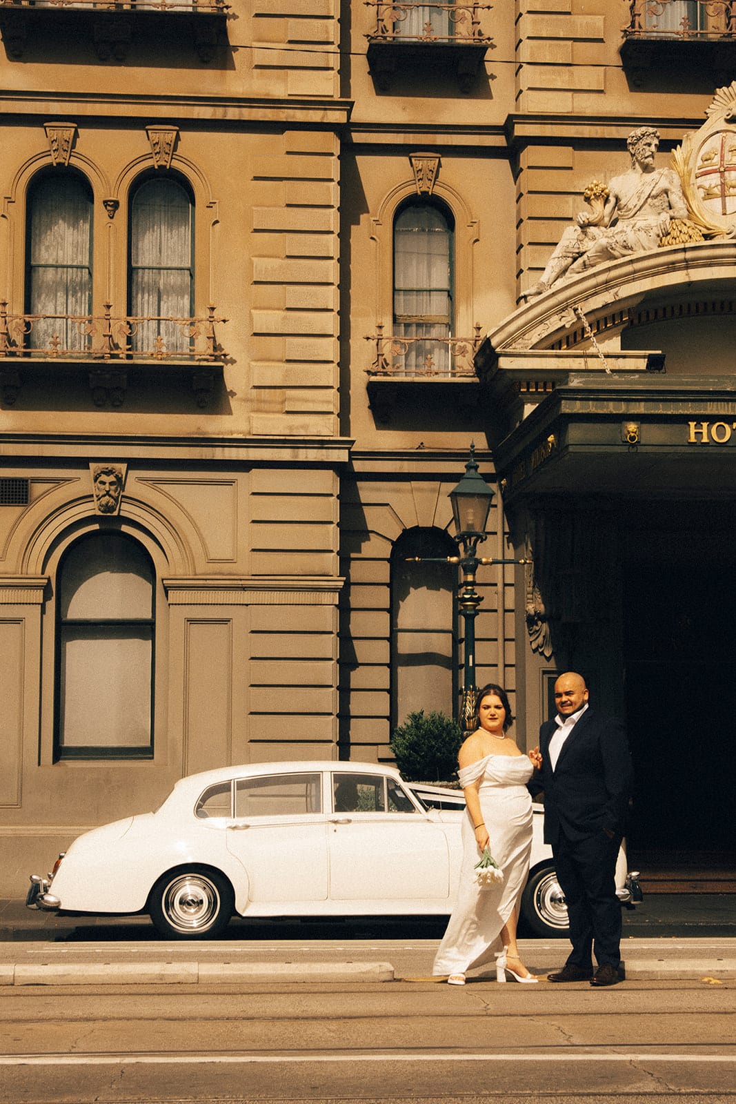 Martina and Diego beside a white vintage car outside the Hotel Windsor