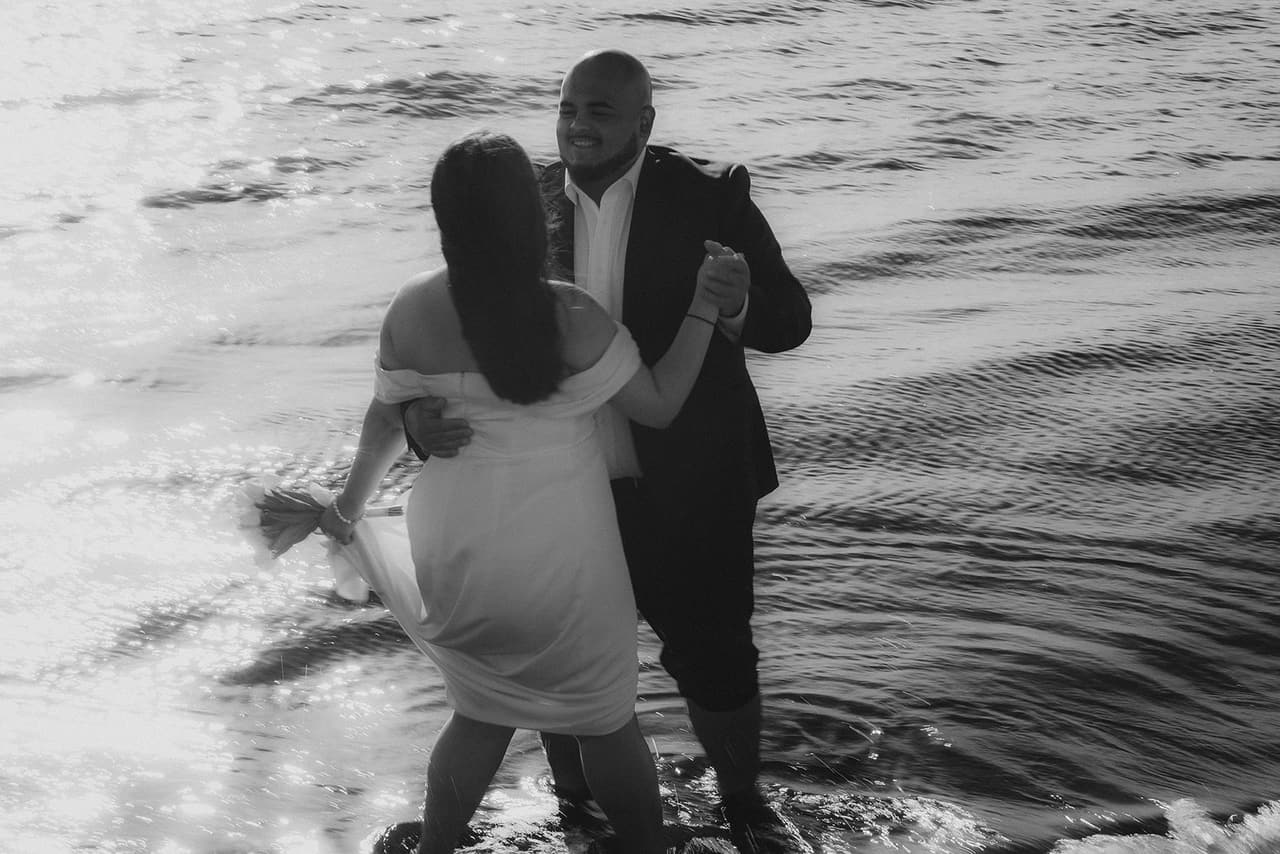 Black and white photo of Martina and Diego dancing in the shallows
