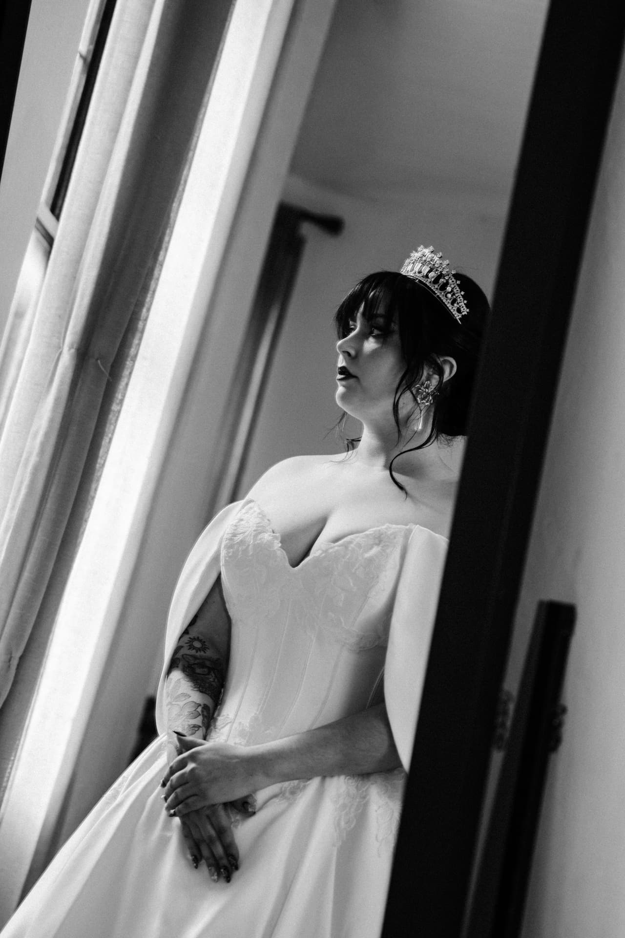Black and white photo of Porscha in a tiara leaning in a doorway and looking out
