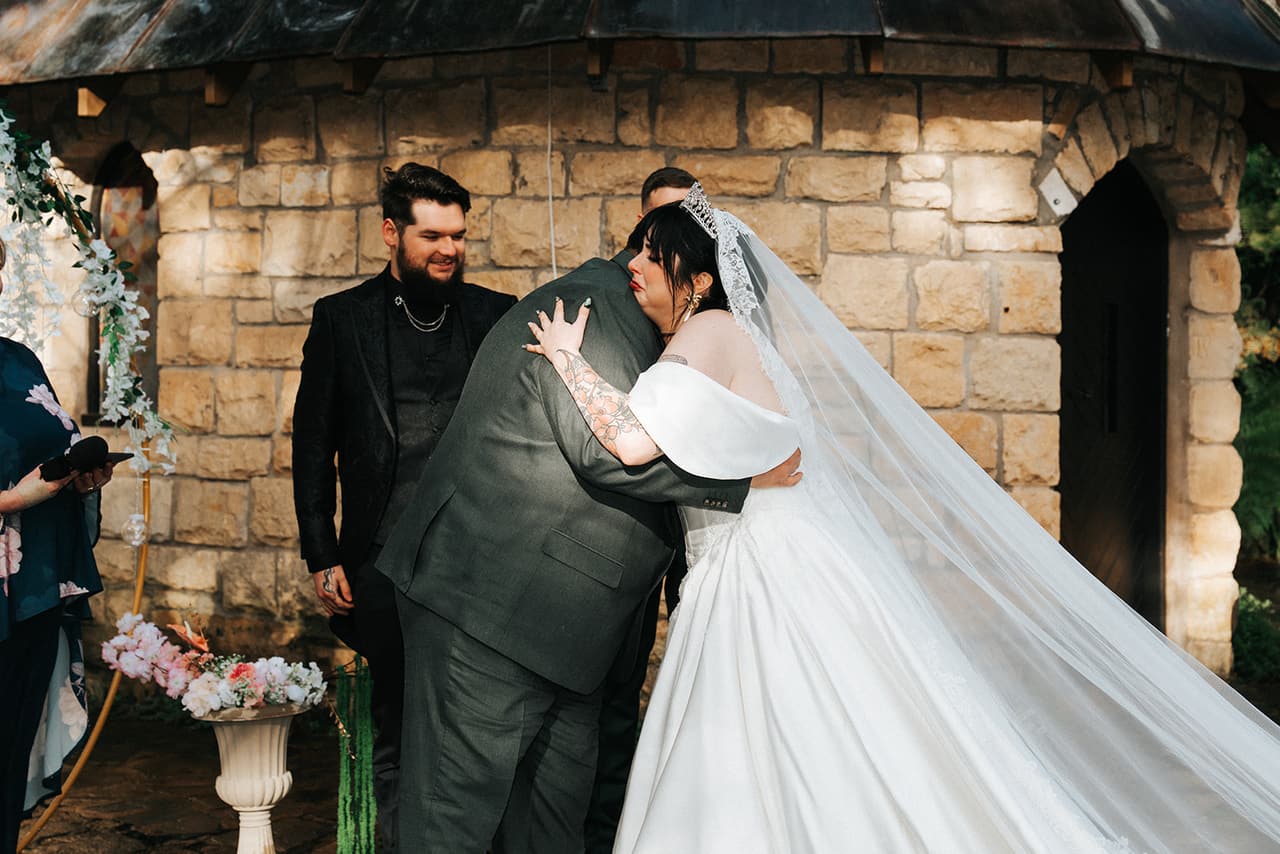 Porscha’s dad hugging her as he gives her away under the floral arch