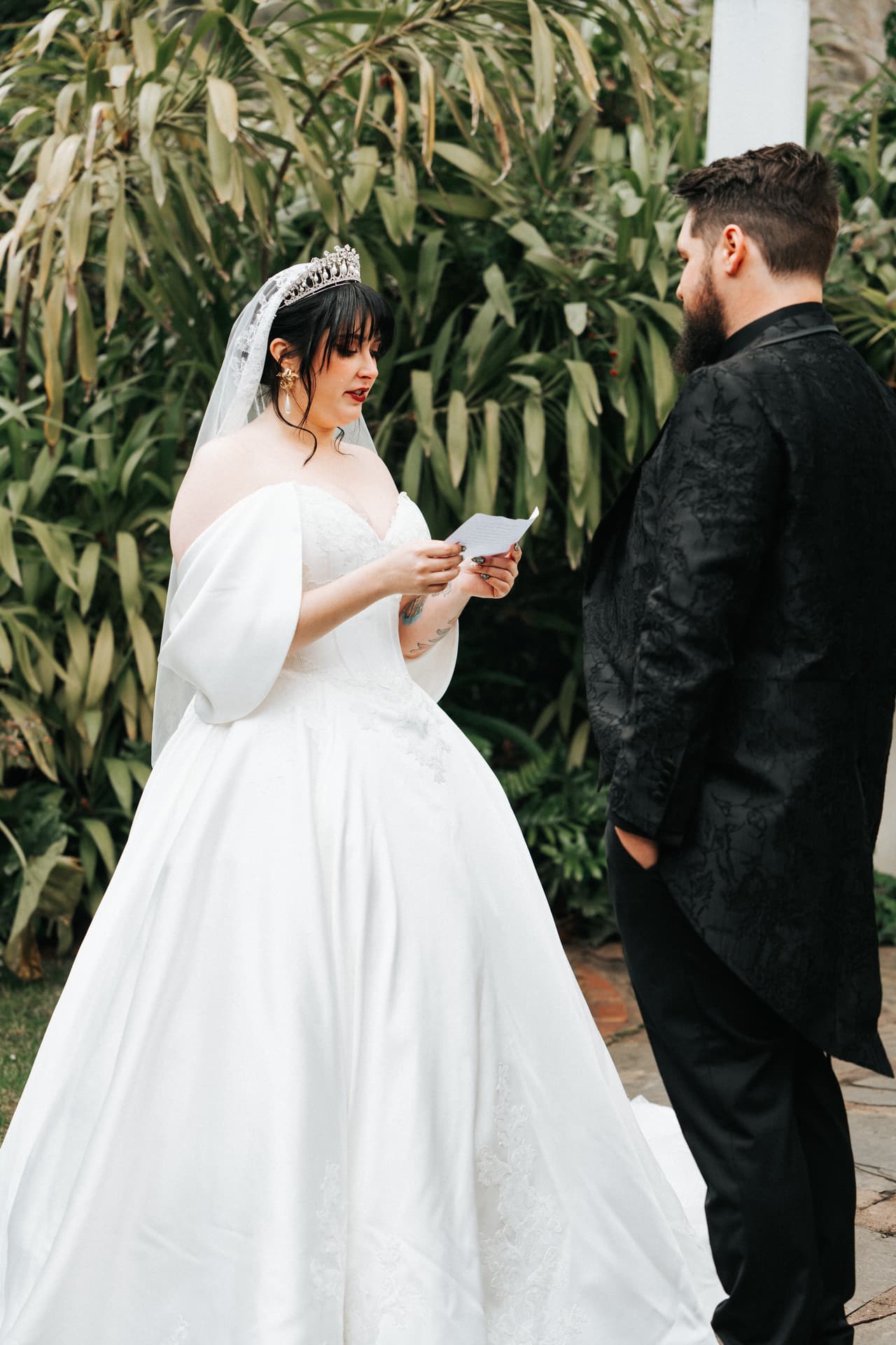 Porscha reading her private vows to Jordan under the white pergola in the garden