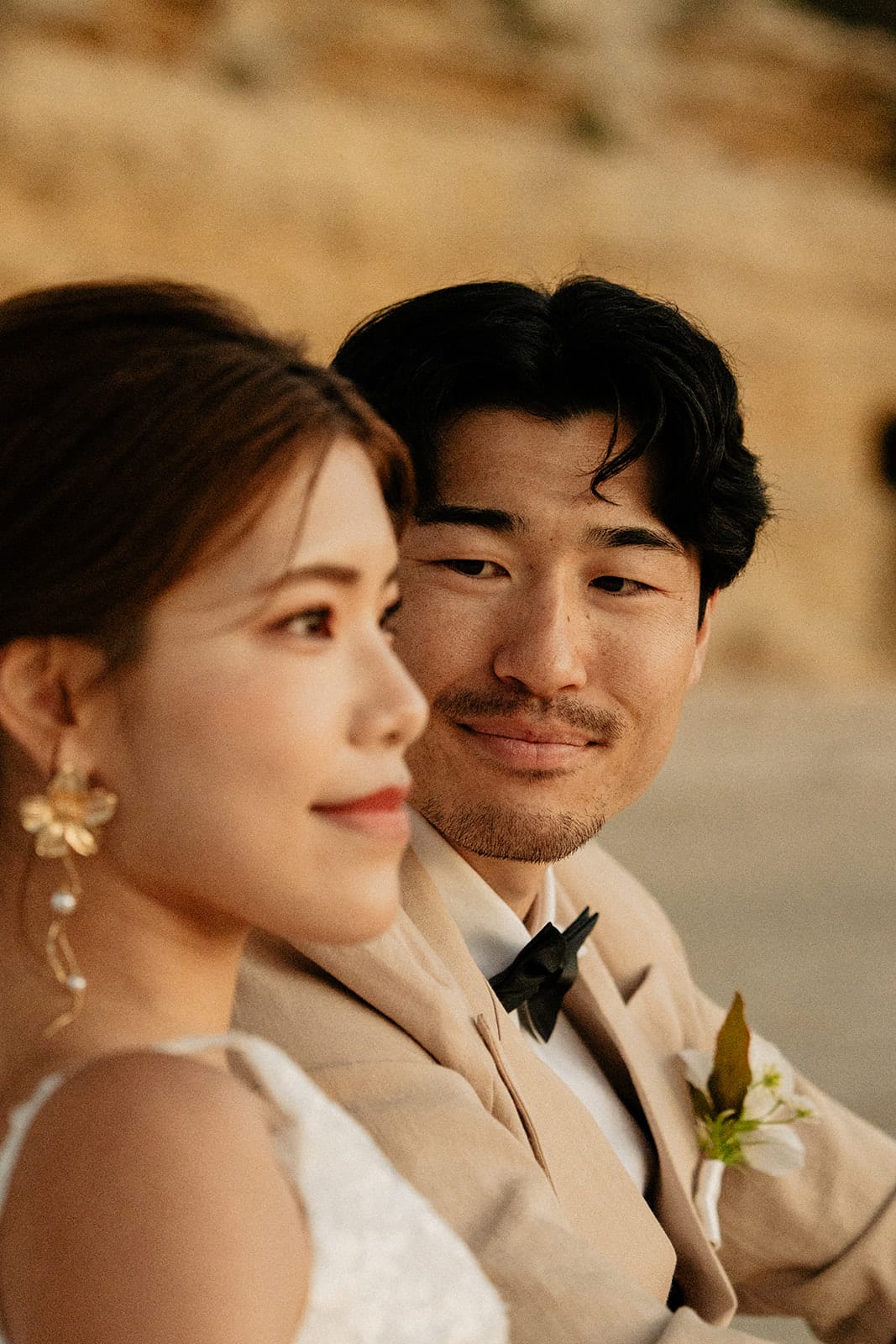 Close up of Sayuri and Shuto cheek to cheek at dusk, the sandstone cliffs behind them