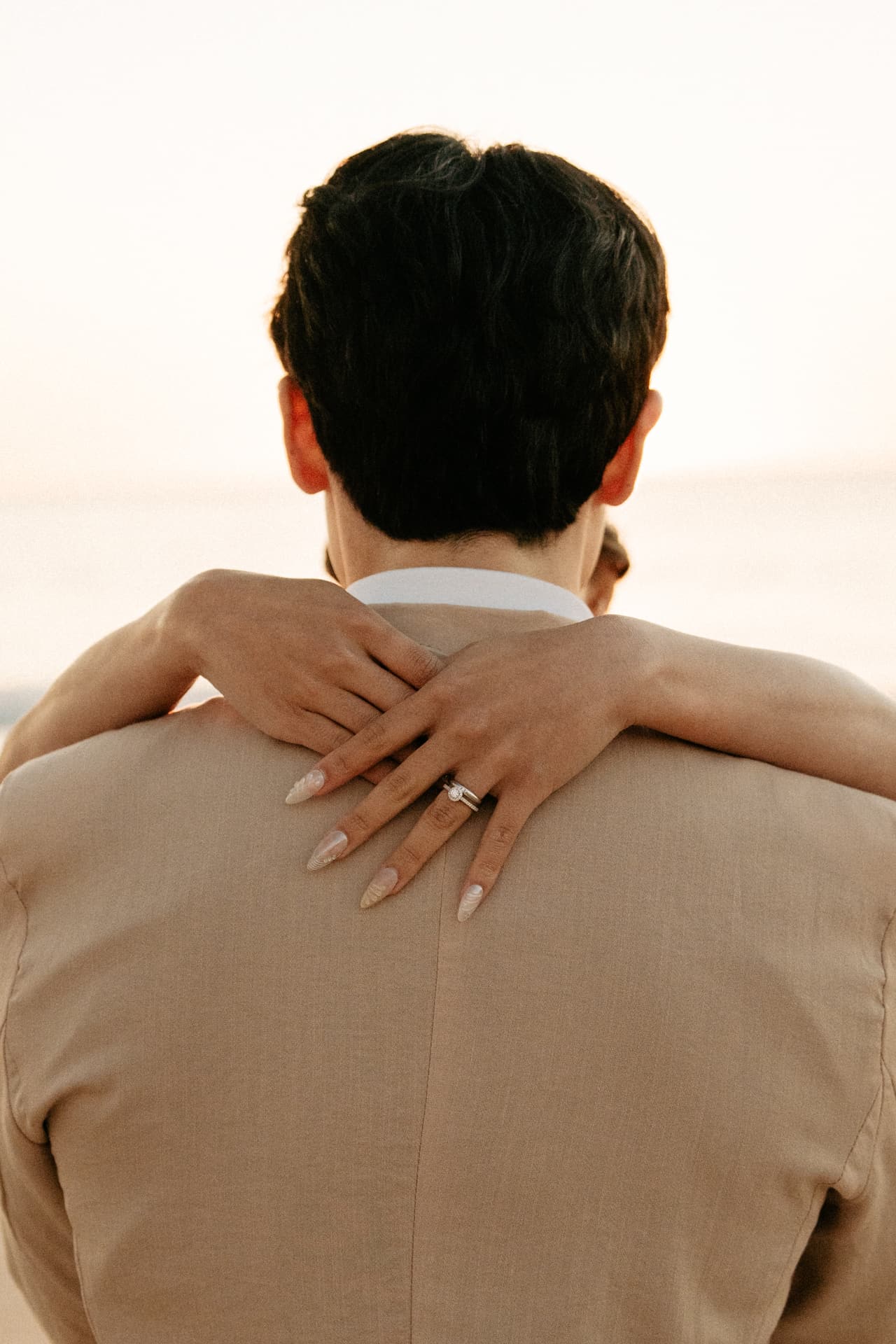 Sayuri’s hands clasped around Shuto’s back, her ring catching the light