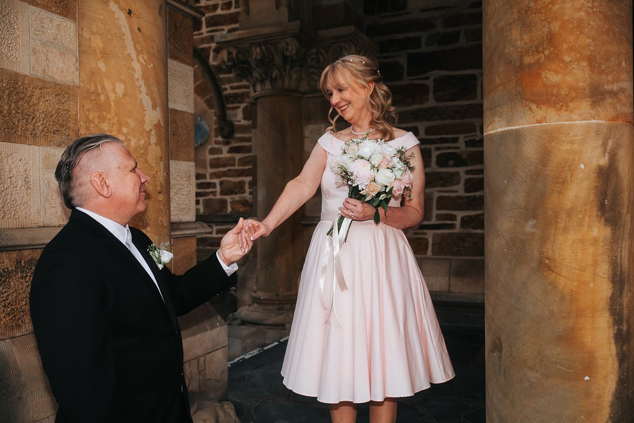 Jon taking Terrie’s hand under a sandstone arch as she smiles down at him
