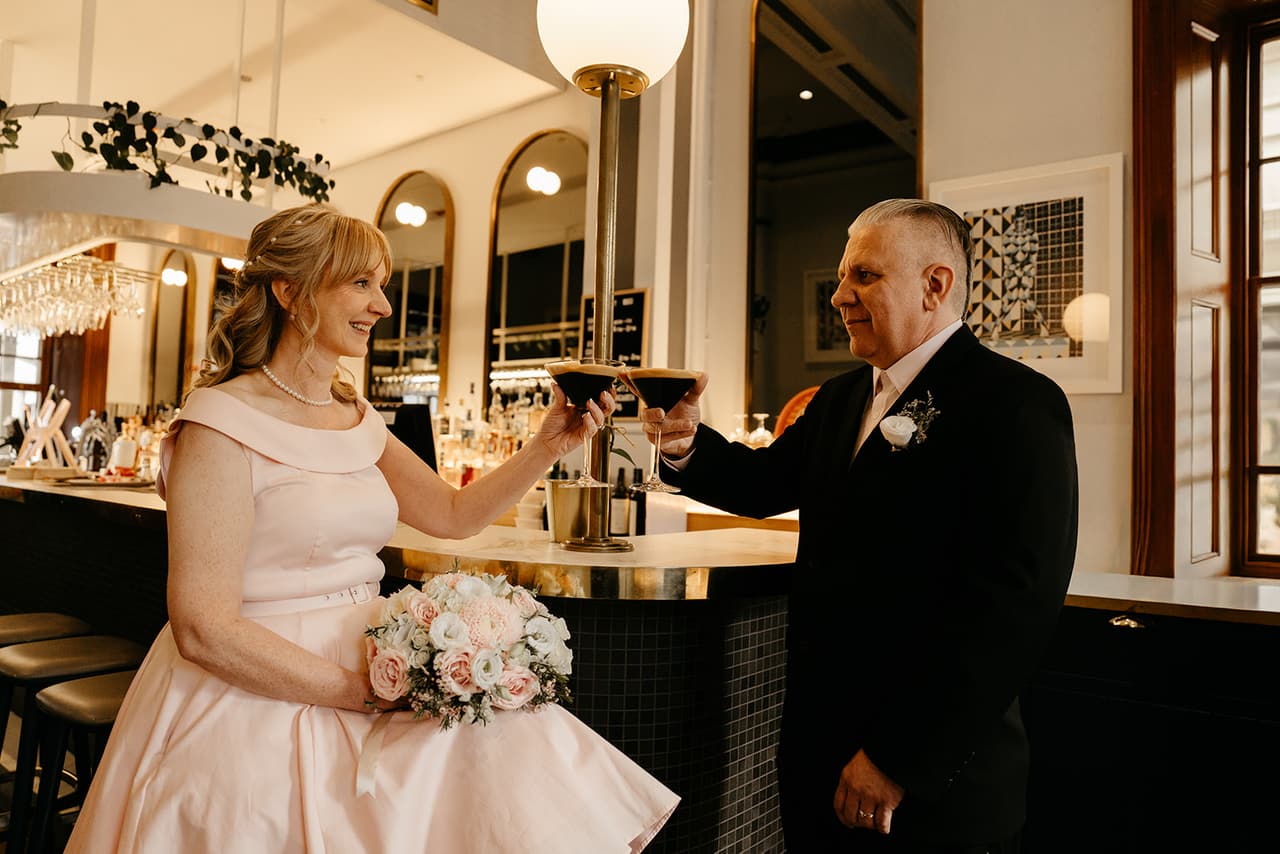 Terrie and Jon raising a glass at the front bar of Treasury 1860